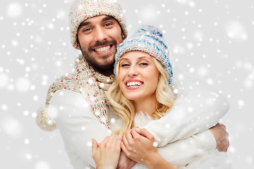 Image showing smiling couple in winter clothes hugging over snow