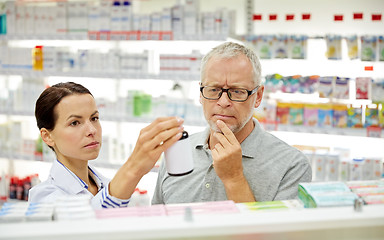 Image showing pharmacist showing drug to senior man at pharmacy