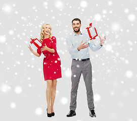 Image showing happy couple with christmas gift boxes over snow