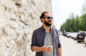 Image showing man with smartphone at stone wall