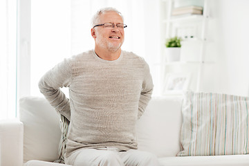 Image showing unhappy senior man suffering from backache at home