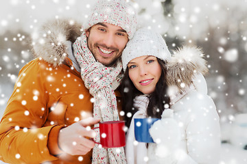 Image showing happy couple with tea cups over winter landscape