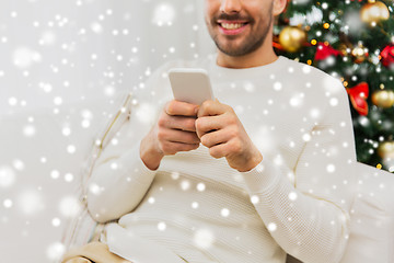 Image showing smiling man with smartphone at home for christmas