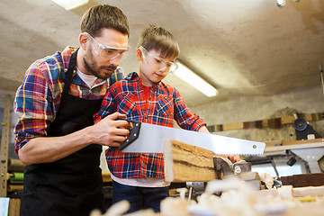 Image showing father and son with saw working at workshop