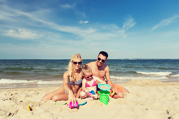 Image showing happy family playing with sand toys on beach