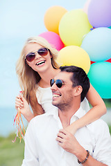 Image showing couple with colorful balloons at seaside