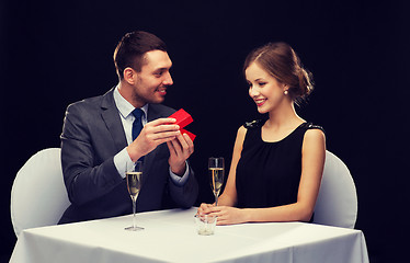 Image showing excited young woman looking at boyfriend with box