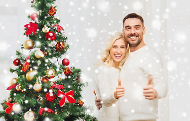 Image showing happy couple showing thumbs up with christmas tree