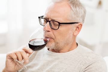 Image showing senior man drinking red wine from glass at home