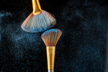 Image showing Two brushes and blue scattered shadows at black background