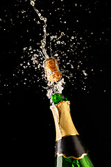 Image showing Green champagne bottle with gold foil and cork explosion