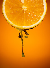 Image showing Fresh orange slice with drops of juice close up on color background