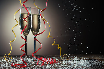 Image showing Two champagne glasses on black background with backlight and snowfall