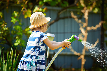 Image showing Little happy girl watering garden