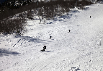 Image showing Skiers and snowboarders on ski slope at sun winter day