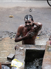 Image showing Streets of Kolkata. Indian people wash themselves on a street