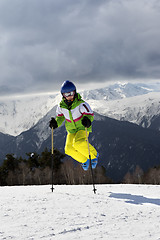 Image showing Young skier jump with ski poles in sun winter mountains and clou