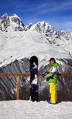 Image showing Young snowboarder with helmet in hands and snowboard on viewpoin