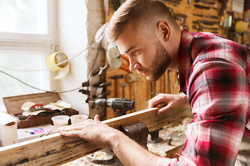 Image showing carpenter working with wood plank at workshop