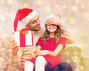 Image showing smiling father surprises daughter with gift box