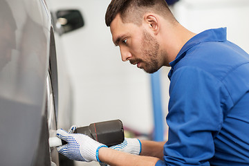 Image showing mechanic with screwdriver changing car tire