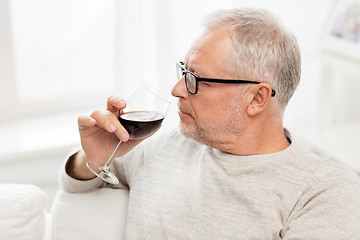 Image showing senior man drinking red wine from glass at home