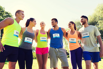 Image showing happy friends or couple with racing badge numbers