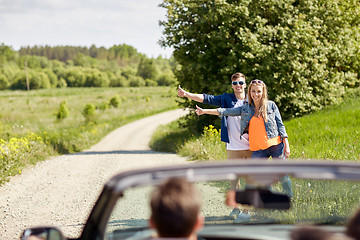 Image showing couple hitchhiking and stopping car on countryside