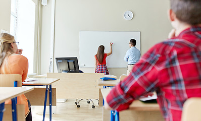 Image showing teacher and student writing on board at school