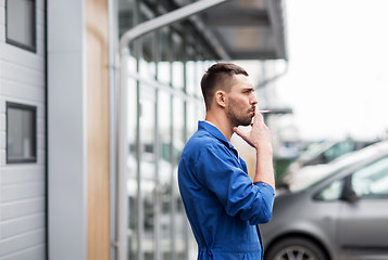 Image showing auto mechanic smoking cigarette at car workshop