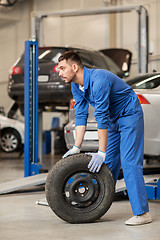 Image showing mechanic with wheel tire at car workshop