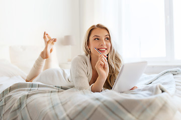 Image showing happy young woman with notebook in bed at home