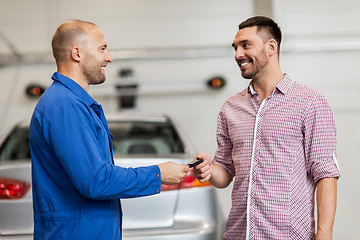 Image showing auto mechanic giving key to man at car shop