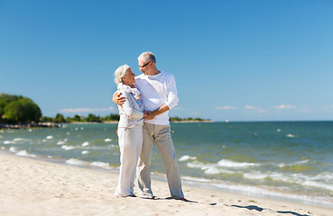 Image showing happy senior couple holding hands on summer beach