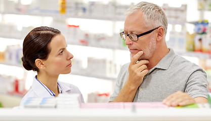 Image showing pharmacist showing drug to senior man at pharmacy