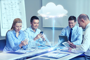 Image showing smiling business people with gadgets in office