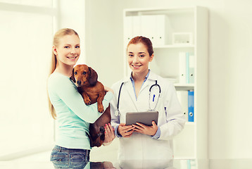 Image showing happy woman with dog and doctor at vet clinic