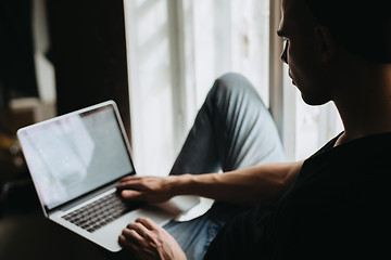 Image showing Young man typing something on a laptop