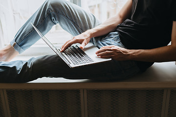 Image showing Young man typing something on a laptop