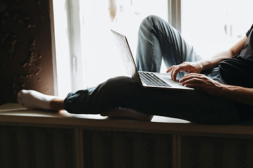 Image showing Young man typing something on a laptop