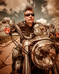 Image showing Biker in a leather jacket riding a motorcycle on the road