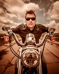 Image showing Biker in a leather jacket riding a motorcycle on the road