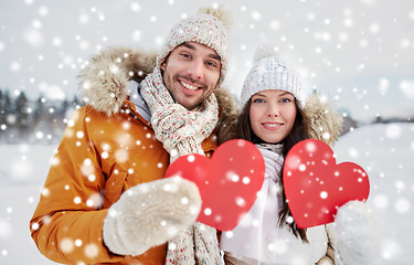 Image showing happy couple with red hearts over winter landscape