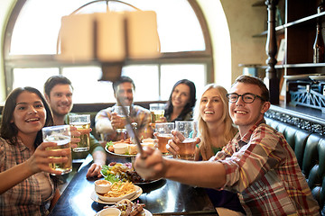 Image showing happy friends with selfie stick at bar or pub