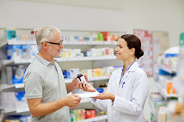 Image showing pharmacist and senior man buying drug at pharmacy