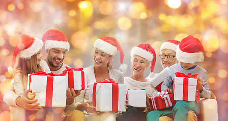 Image showing happy family in santa hats with gift boxes