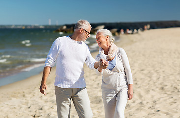 Image showing happy senior couple holding hands on summer beach