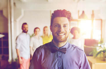 Image showing happy young man over creative team in office