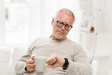 Image showing senior man with coffee looking at wristwatch