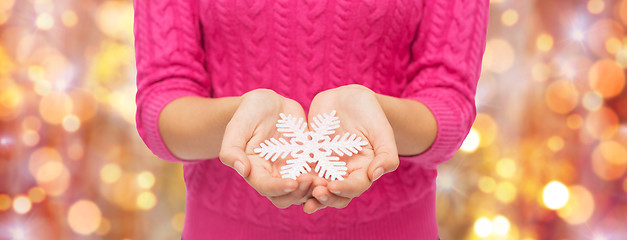 Image showing close up of woman in sweater holding snowflake